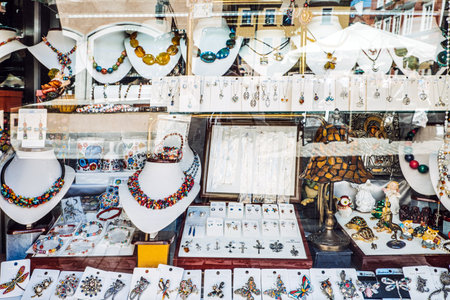 A vibrant jewelry shop window with an array of necklaces, earrings, brooches, and decorative pieces, showcasing artistic designs and intricate detailing.の写真素材