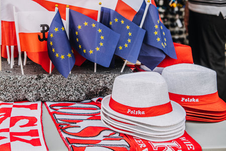 Polish and European Union flags with white hats and scarves showcasing national pride at an outdoor market.の写真素材