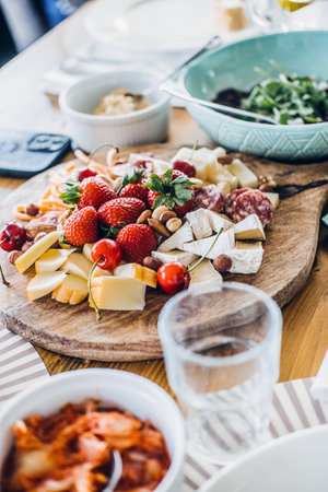 Rustic farm-to-table dining table with fresh charcuterie, floral centerpiece, and artisanal dishes, showcasing natural living and gourmet simplicityの写真素材