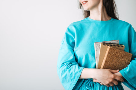 Smiling woman holding eco-friendly notebooks in minimalist style. Sustainable stationery trends, cork accessories, and conscious consumerism for a zero-waste lifestyle.の写真素材
