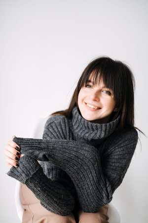 Young woman smiling in cozy sweater, casual winter fashion, minimalist style, warm and comfortable,...