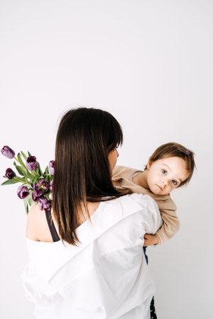 Mother and child admiring purple tulips. Real-life family moments, Mothers Day celebration, natural...