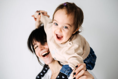 Mother carrying daughter on shoulders, playful bonding moment. Family love, joyful motherhood,...