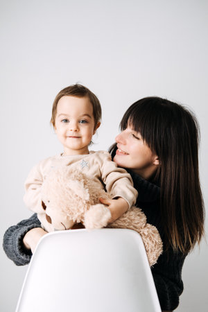 Mother and child bonding with a toy bear, family love, early childhood, tender moments, cozy indoor portrait, maternal affection, parenthood.の写真素材