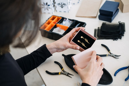 Jewelry artisan showcasing handmade earrings in stylish packaging. Small business branding, luxury packaging, jewelry marketing, boutique presentation, craft businessの写真素材