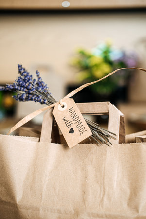 A brown paper gift bag with a Handmade with love tag and a sprig of dried lavender attached. Handmade gifts, small business packaging, craft market appeal, eco-conscious brandingの写真素材