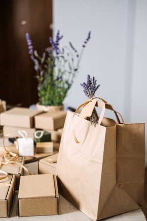 Natural soap gift boxes and kraft bags are arranged on a table with floral decor. Handmade gifts,...