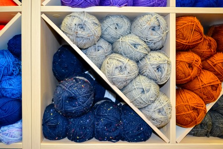 Shelf with colorful colors wool yarn balls on shop display stand for saleの写真素材