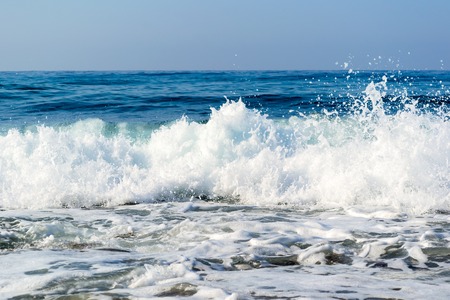 Sea waves breaking on a stony beach, forming sprays and splashesの写真素材