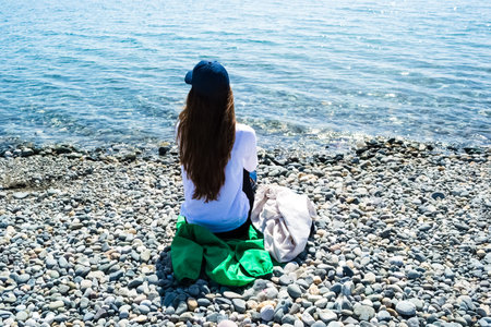 Young woman sitting rear view looking at the sea