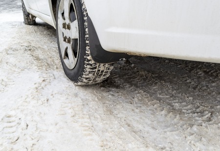 Car tyres on winter road covered with snowの写真素材