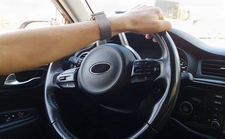 Male driver's hand holding a steering wheel
