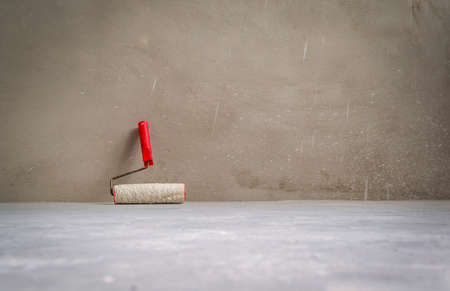 Paint roller in empty room on cement floor. Grunge interior background.の写真素材