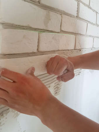 Laying gypsum tiles in rows on the wall with male hands. Home repair.の写真素材