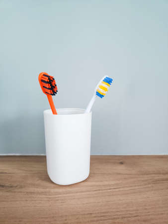 Two colored toothbrushes in white plastic glass.の写真素材