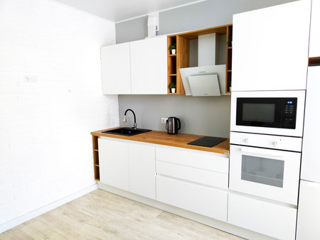 Minimal white kitchen modern scandinavian interior with cooker hood on wooden countertop. Real photo