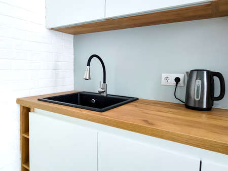 Black sink with flexible faucet in stylish Scandi kitchen interiorの写真素材
