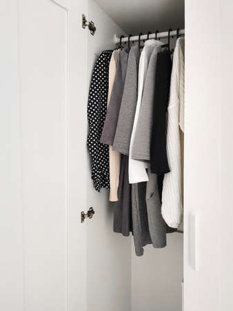 Wardrobe with basic clothes in room scandi interior. Neutral colors: white, black, beige.の写真素材