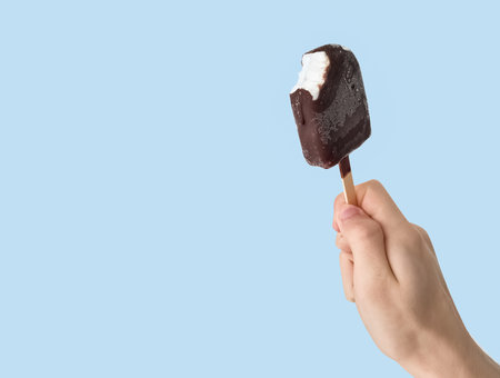 Teen-ager holding eskimo ice cream on light blue background.の写真素材