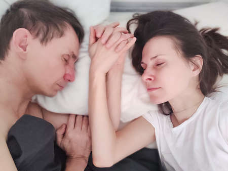 Loving couple sleeping and holding handsの写真素材