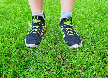 Boy standing on the grass lawn. Feet in sneakersの写真素材
