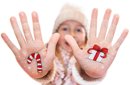 Happy girl demonstrating painted Christmas symbols on her hands. Santa Claus, Christmas tree, Snow man and etcの写真素材