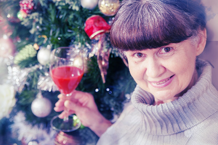 Mature age good looking woman against of Christmas tree. Christmas backgroundの写真素材