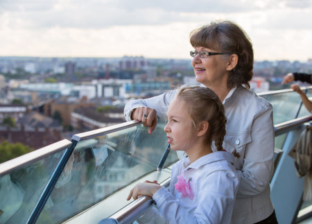 Elderly woman and granddaughter enjoying the London view. Background includes modern building City...