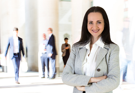 Attractive young businesswoman portrait with business people walking on the backgroundのeditorial素材