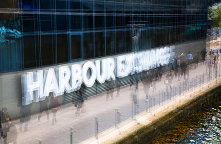 Multiple exposure effect image. Office workers walking against of Harbour Exchange sign