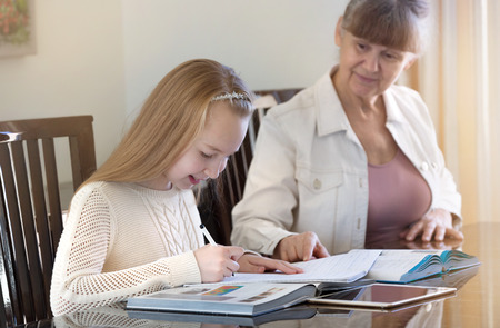 10 years old girl and her teacher. Little girl study during her private lesson. Tutorial and educational concept.の写真素材