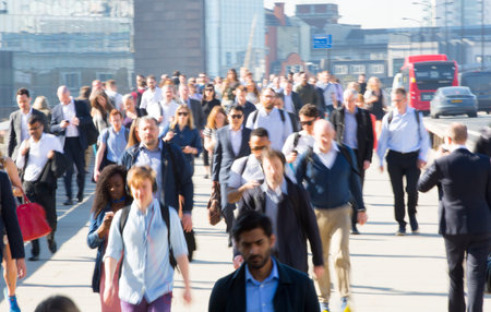 London, UK - April 19, 2018: Lots of office workers crossing the London bridge in early morning on...