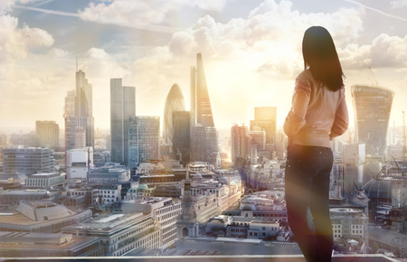 Young woman looking over the City of London at sun set. Future, new business opportunity and business success concept.の写真素材