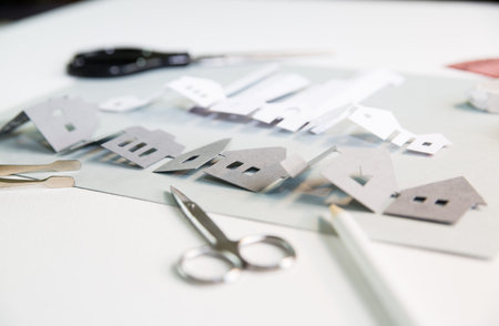 Paper cut design elements with tools: scissors, knife, pare, glue etc. Creation a city view in progress. Creativity, education, hobby, innovation and inspiration concept.の写真素材