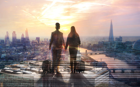 Two travellers with suitcases looking over the  City of London at sunset before departure. Future,...