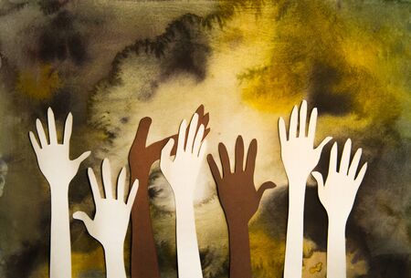 Humans hands raised up celebrating togetherness, teamwork and support. Paper made backgroundの写真素材