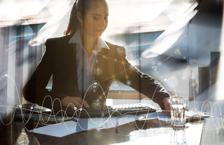 Attractive business woman working by her desk in office against sun light. Business conceptの写真素材