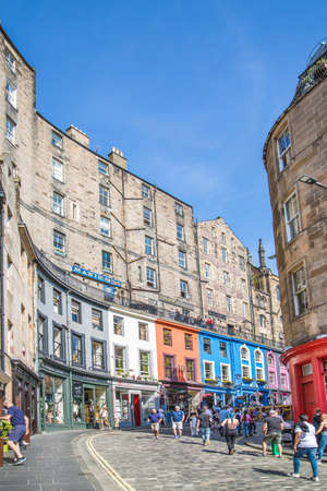 Scotland, Edinburg - August 24, 2021: Victoria street with beautiful curve and colourful shopfronts, built in 1860th and designed in the fashionable Scots Baronial style. People walking on the roadのeditorial素材