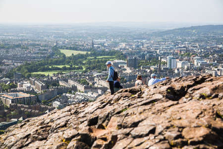 Scotland, Edinburgh, UK - August 26, 2021: Holyrood park and ancient volcano. People climbing on top of the Rock of Edinburgh.  City of Edinburgh view from the mountainのeditorial素材