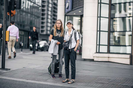 London, UK - June 21, 2022: Two young girls with travel bags are crossing the road in the City of London. Commuters, office workers, City of London life, Street photographyのeditorial素材