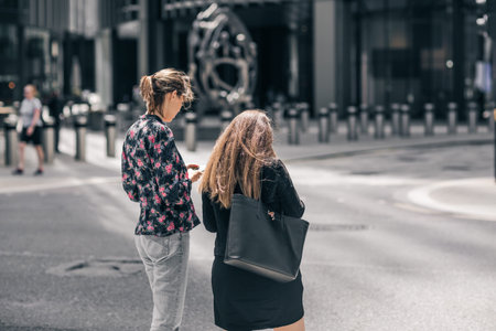 London, UK - 21 June, 2022: Young woman searching information with mobile phone in the City of...
