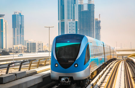 Dubai, UAE - September 2, 2022: Dubai metro railway track view with City buildings and approaching...
