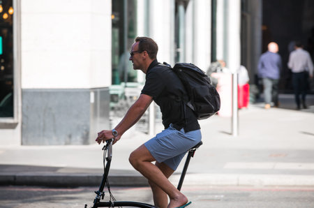 London, UK - June 22, 2022: Young man cycling at work by bike and make a spot by the traffic lights....