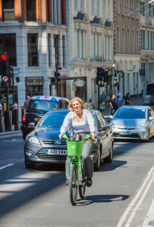 London, UK - June 22, 2022: Young woman cycling at work by bike. People cycling into the City of Londonのeditorial素材