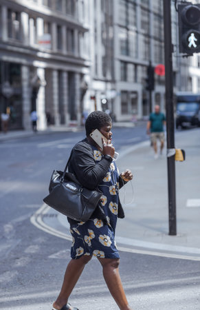 London, UK - June 22, 2022: Woman with mobile phone is walking  in the City of London