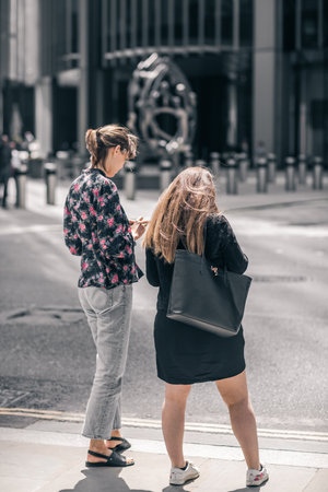 London, UK - June 22, 2022: Young women searching with mobile phone in the City of Londonのeditorial素材