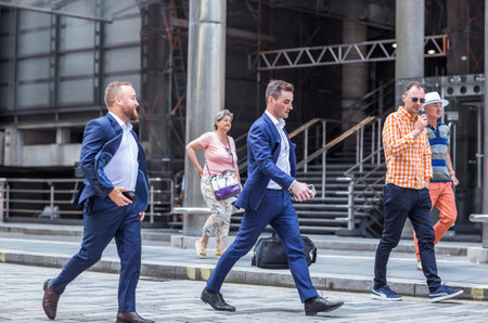 London, UK - June 22, 2022: Business people walking in early morning by the Bank of England. Busy...