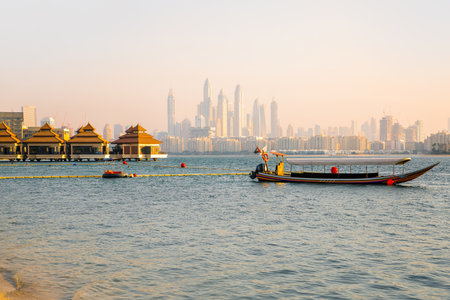 Dubai, UAE September 1, 2022: Traditional boat and Dubai marina at the background at sunsetのeditorial素材
