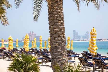 Dubai, United Arab Emirates - August 26, 2023:  White sand beach and Beas beds with umbrellas at Palm Jumeirahのeditorial素材
