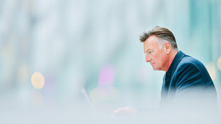 Portrait of senior businessman using laptop computer in the city at nightの素材